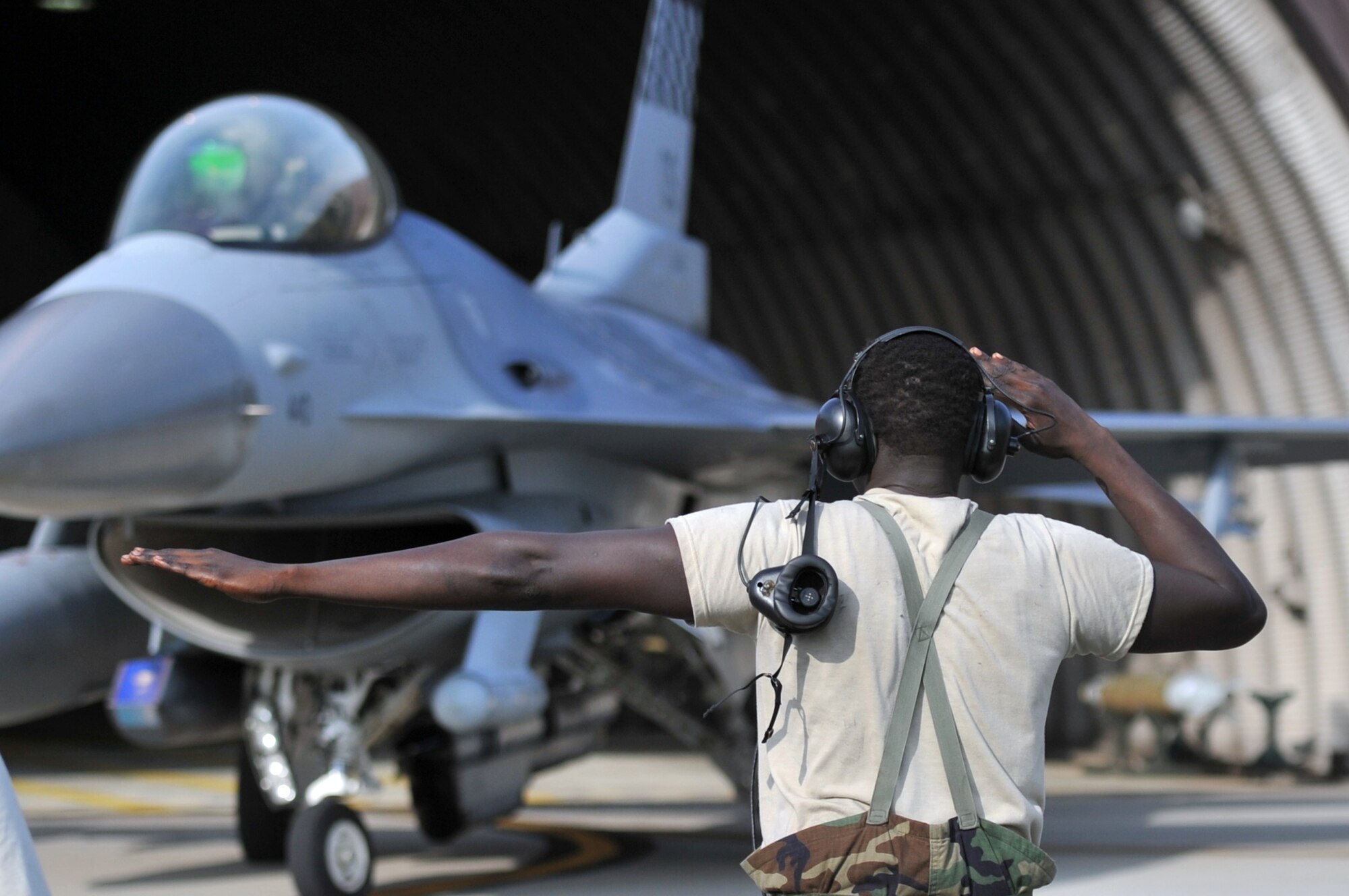 Senior Airman Tethloach Wuol, 36th Fighter Squadron crew chief, guides an F-16 Fighting Falcon out of a hardened aircraft shelter at Osan Air Base, Republic of Korea, July 25, 2012. Osan Airmen are in the fourth simulated wartime contingency exercise executed in 2012 that test the base’s ability to defend and execute the mission in a heightened state of readiness. Osan’s Airmen provide combat ready forces for close air support, air strike control, counter air, interdiction, theater airlift, and communications in the defense of the Republic of Korea. (U.S. Air Force photo/Staff Sgt. Craig Cisek) 