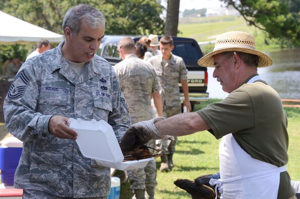 Chief Master Sgt. Israel Rosado receives his lunch of roasted ears of corn and bratwurst at the Dobbins Annual Corn and Sausage Roast held at the base lake July 18. (U.S. Air Force photo/Don Peek)