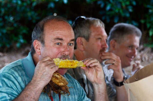 Zach Ethridge from the 94th Communications Squadron enjoys a roasted ear of corn at the annual Dobbins Corn and Sausage Roast held at the Base lake July 18. (U.S. Air Force photo/Don Peek)