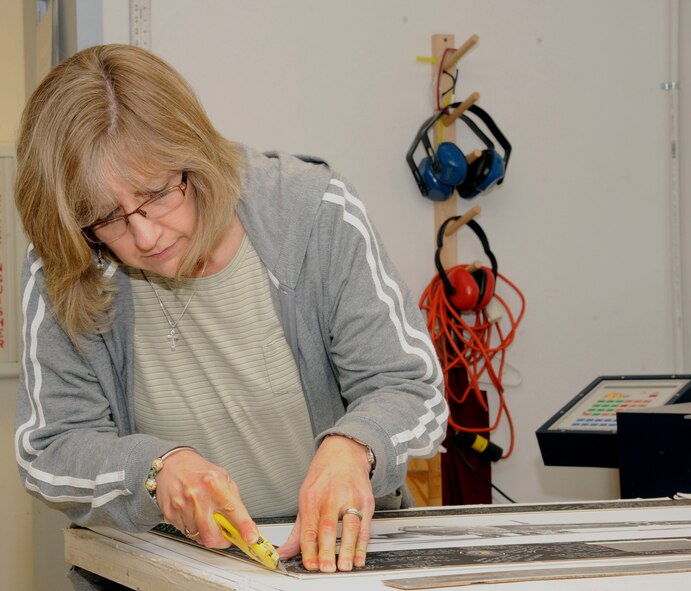 Brenda Porter, trims a picture mat in preparation for framing at the Art and Crafts frame shop on Barksdale Air Force Base, La., July 25. The frame shop's constructs and sells its own frames allowing Airmen to pick and choose the style of frame they would like to use to house a photo. (U.S. Air Force photo/Airman 1st Class Andrew Moua)(RELEASED)