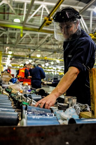 Petty Officer Jarred Hart, Navy Munitions Command mine shop mineman, reaches for a booster and arming device to be placed in a training mine during an exercise July 19, 2012 at Joint Base Charleston – Weapons Station, S.C. The active-duty Sailors in the mine shop are in a deployable status and ready to report to the fleet at any time, where they will maintain and deploy mines aboard aircraft carriers. (U.S. Air Force photo by Senior Airman Dennis Sloan)