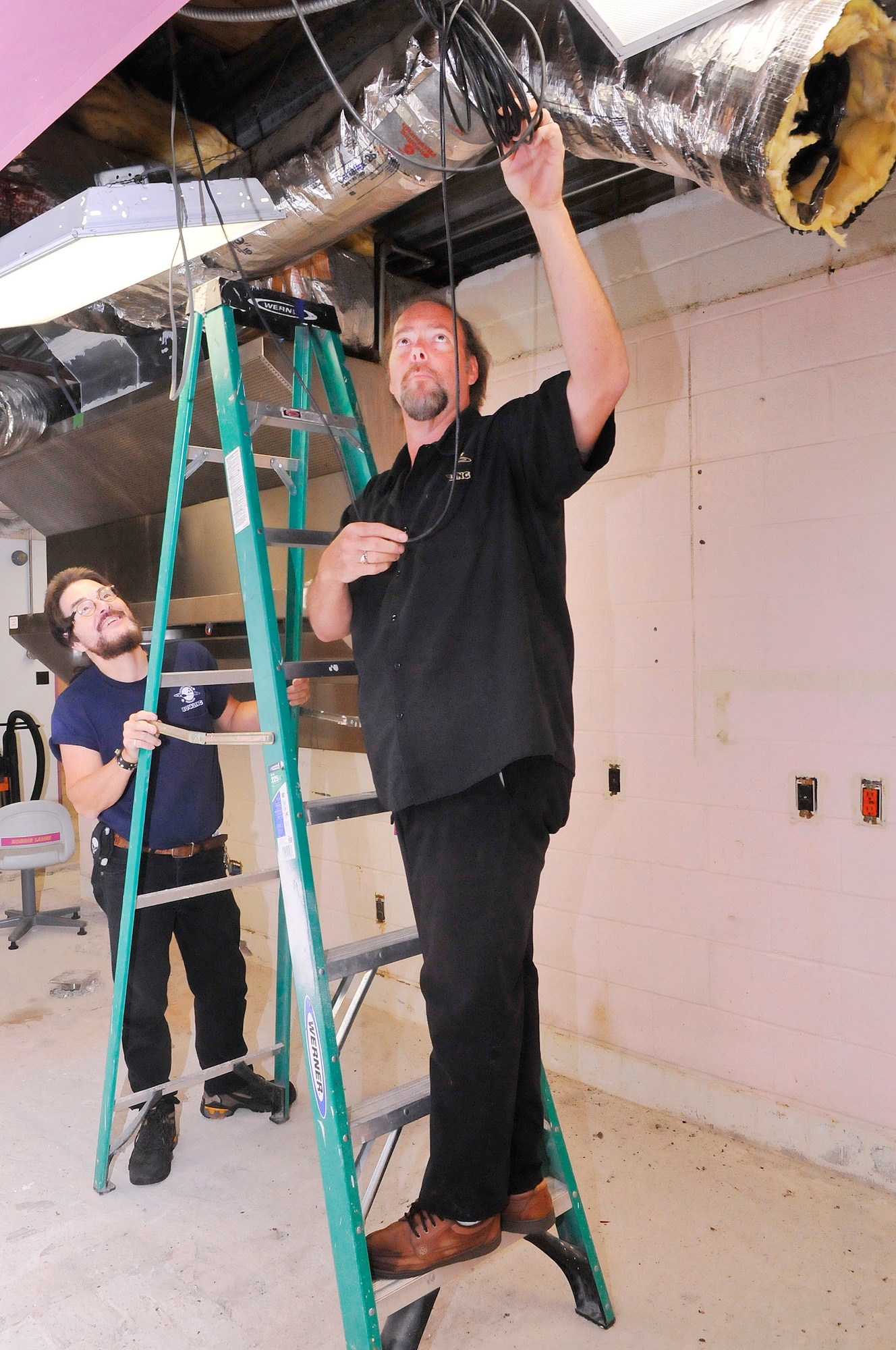 L-R, Fred Babcock, Robins Bowling Center janitorial technician, holds a ladder for Rick Catlett, maintenance manager, to check on some cable during renovation of On Spot Cafe at the Robins Bowling Center. (U. S. Air Force photo/Sue Sapp)