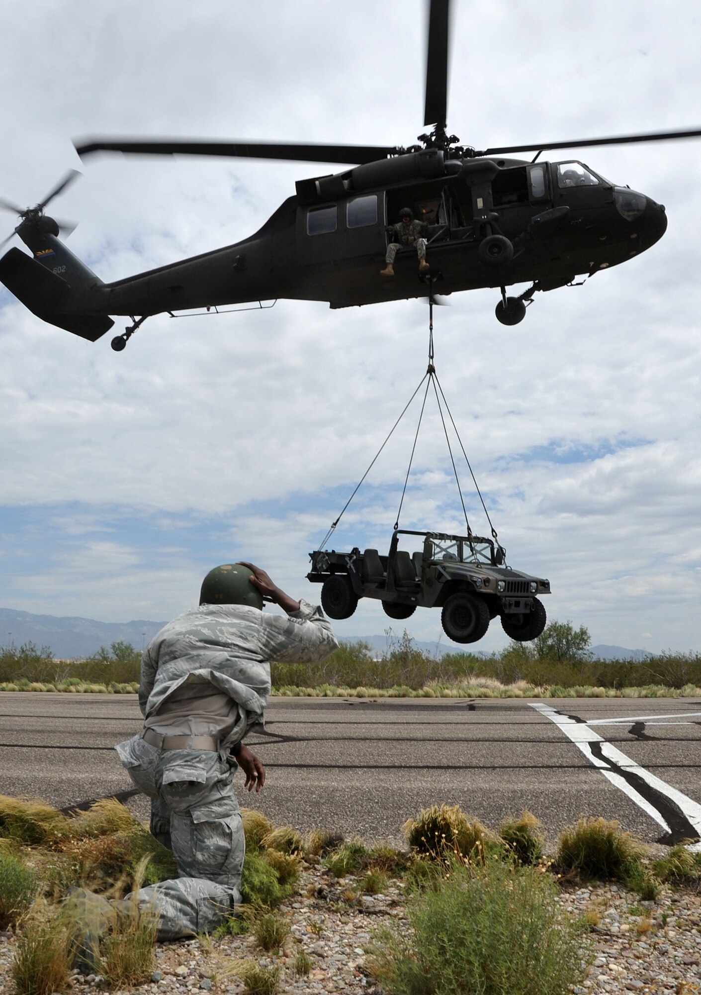 Tech. Sgt. Aaron Doss, a 943rd RQG Reserve security forces Airman, observes a Humvee being lifted off the ground by a UH-60 Black Hawk helicopter. Volunteers from all braches stationed at Davis Monthan Air Force Base, Ariz. trained on how to safely maneuver around heliocopters in a deployed environment with an Arizona Army National Guard UH-60 Black Hawk helicopter. (U.S. Air Force photo/ Master Sgt. Luke Johnson) 