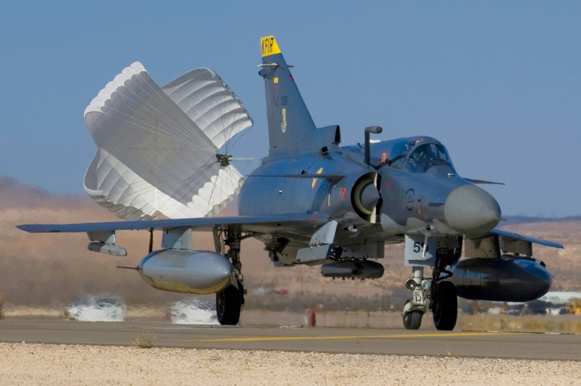 A drag chute deploys from a Colombian air force Kfir upon landing during Red Flag 12-4 July 18, 2012, at Nellis Air Force Base, Nev. Coordination between pilots and the ground crew prevent the chutes from becoming a hazard after jettison. (U.S. Air Force photo by Staff Sgt. William P.Coleman)
  

