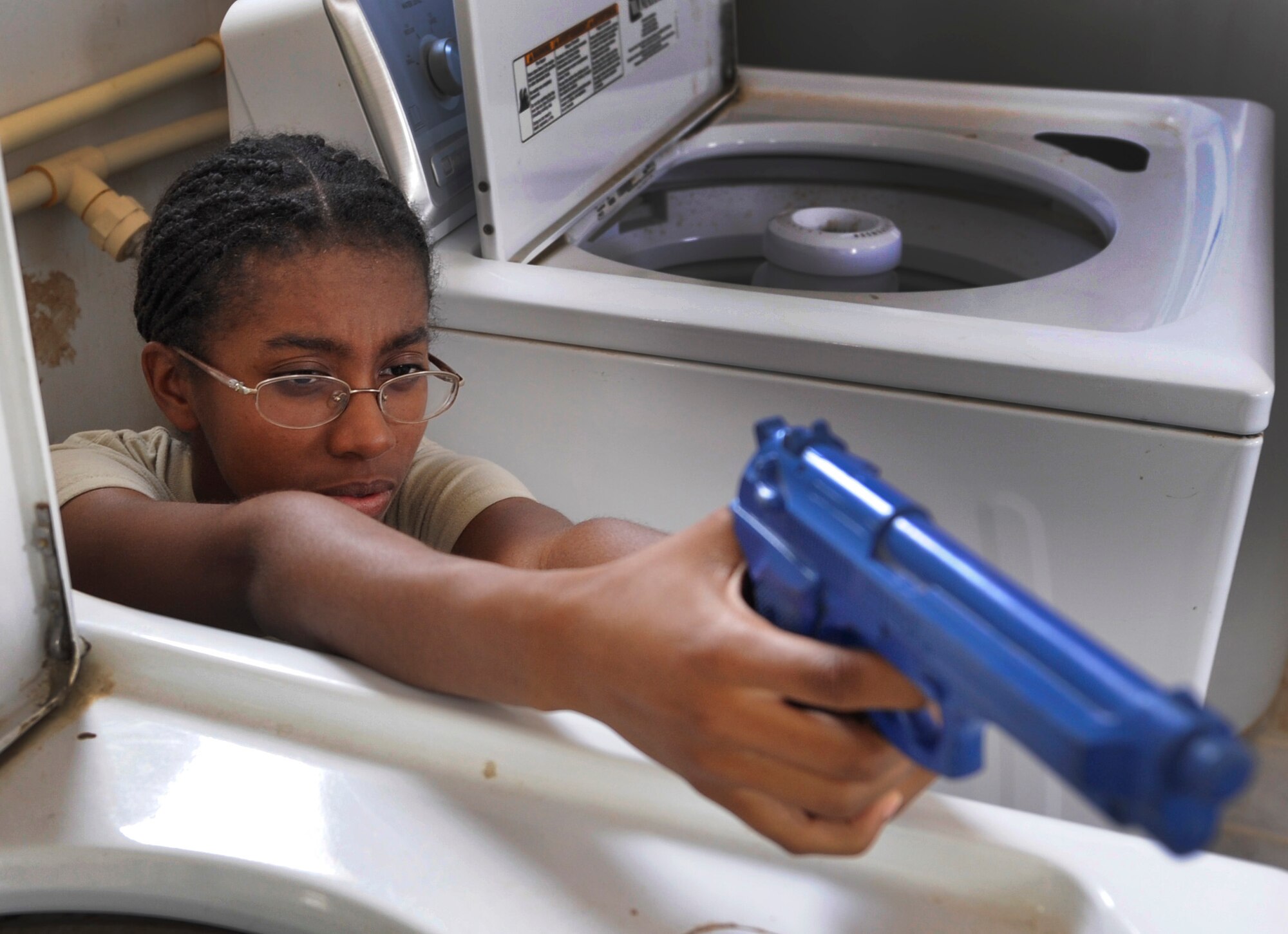SOUTHWEST ASIA – Acacia Miller, Air Force Academy cadet and simulated active-shooter, waits for security forces to breach the doors of the laundry facility during an exercise here July 23. Accurate and timely descriptions of active-shooters help security forces Airmen gather crucial information to find the suspect before they cause further harm to themselves or others. (U.S. Air Force photo/Staff Sgt. Alexandra M. Boutte)