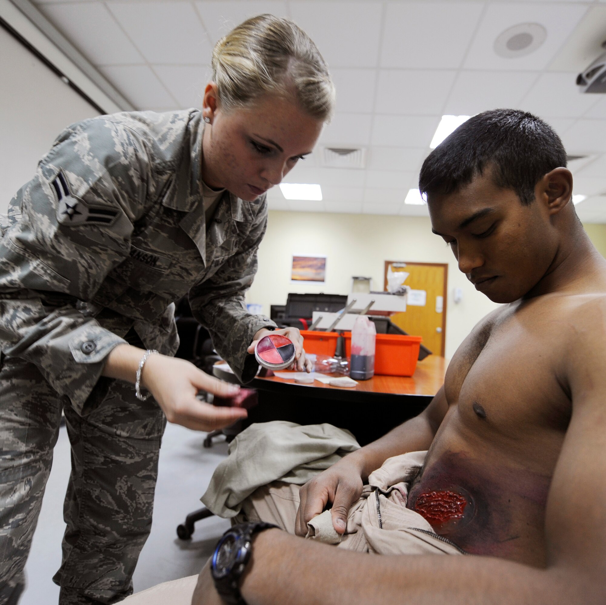 SOUTHWEST ASIA – Airman First Class Emilee Germanson, 386th Expeditionary Medical Squadron, puts moulage paint on a simulated victim, Jason David, Air Force Academy cadet, before an active-shooter exercise here July 23. The exercise tested the base’s ability to respond to a crisis situation in the event that a real-world threat occurs. (U.S. Air Force photo/Staff Sgt. Alexandra M. Boutte)