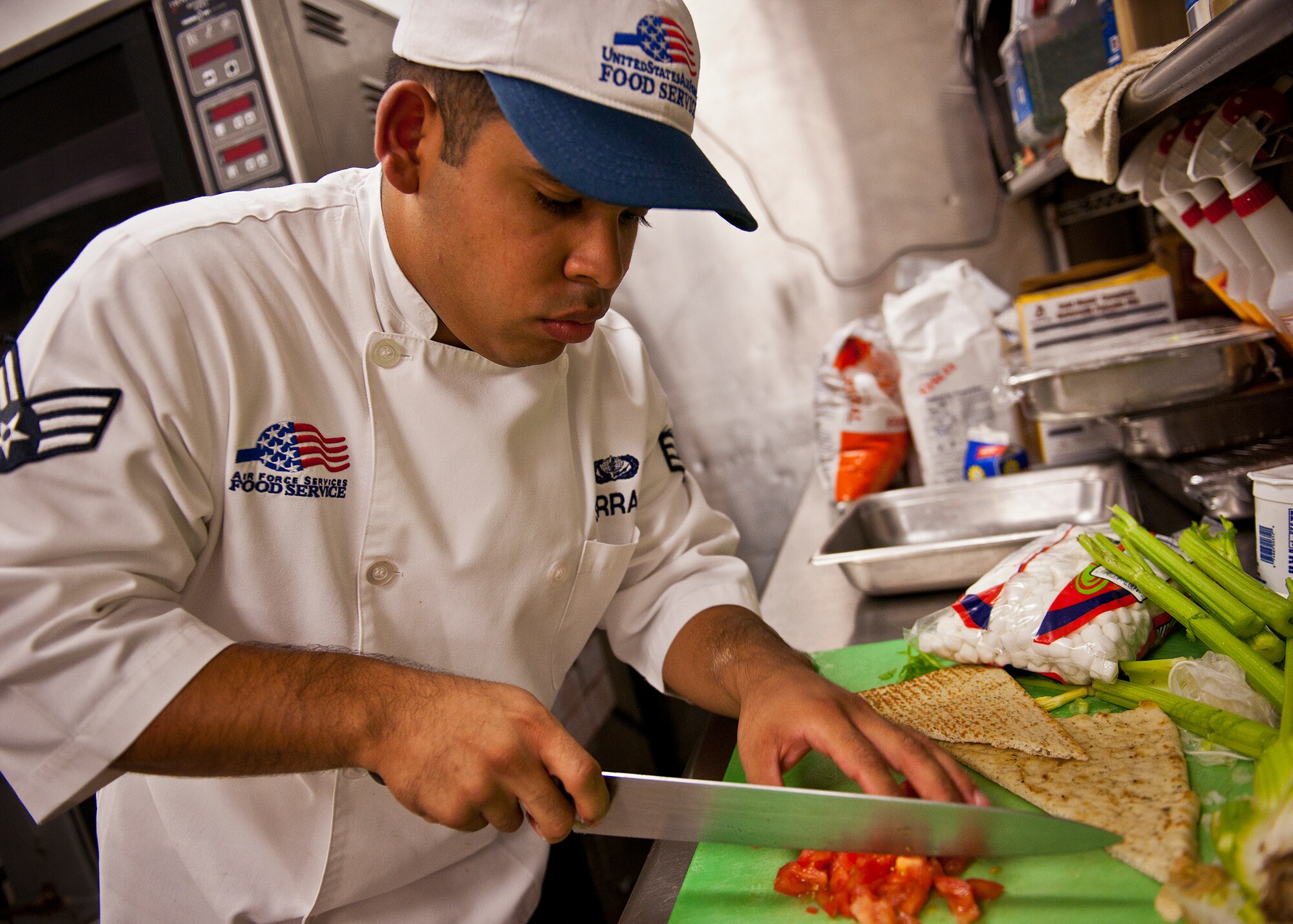 Senior Airman Gamaliel Serrano dices up tomatoes to top off his dish during the base’s first “Chopped” cooking competition July 24 at Eglin.  Five Airmen from the 96th Force Support Squadron had an hour to cook a meal with three secret ingredients.  Serrano’s dish went on to win the contest.(U.S. Air Force photo/Samuel King Jr.)