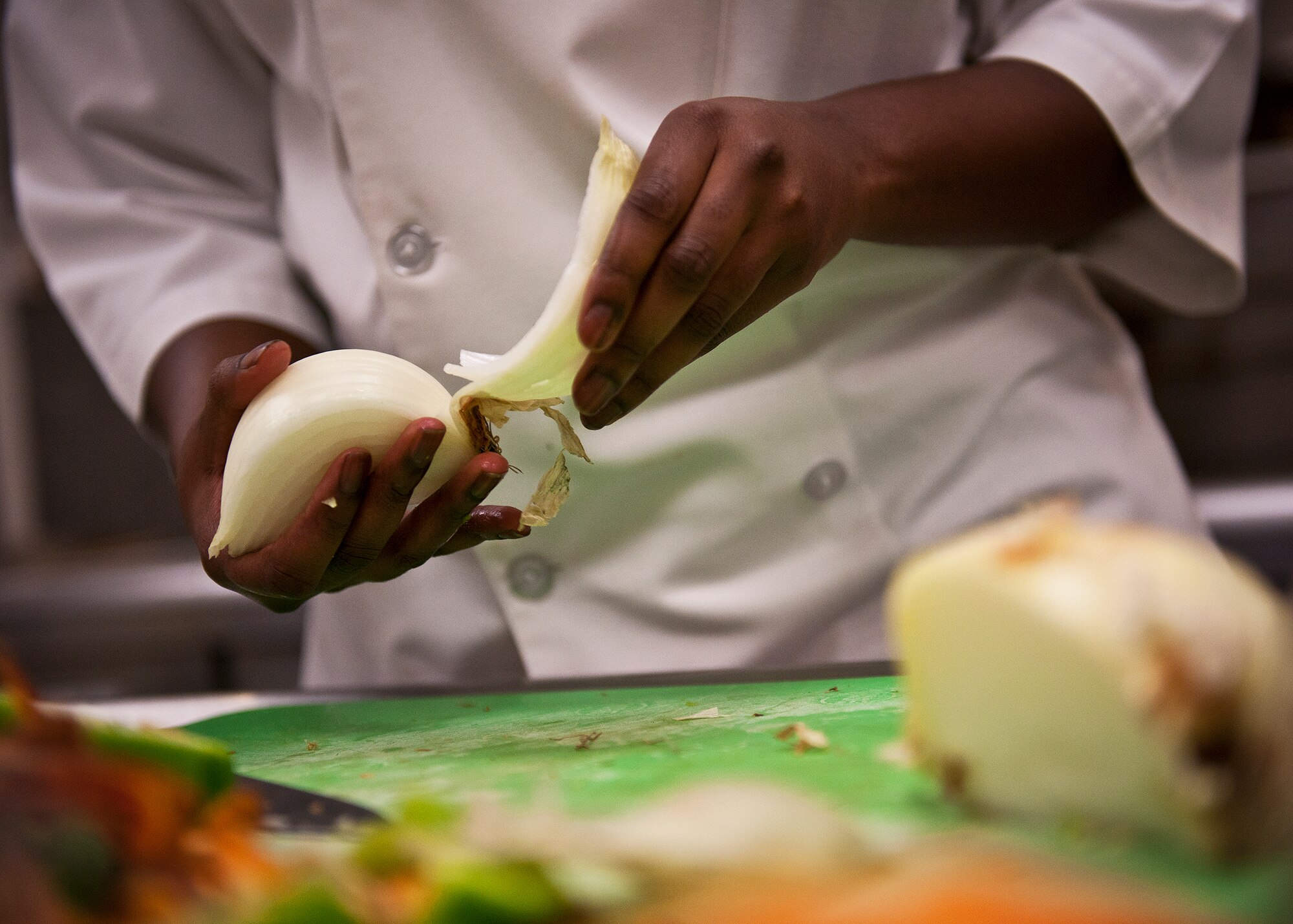 Senior Airman LaToya Grover peels the skin from an onion during her meal preparation for the base’s first “Chopped” cooking competition July 24 at Eglin.  Five Airmen from the 96th Force Support Squadron had an hour to cook a meal with three secret ingredients.  (U.S. Air Force photo/Samuel King Jr.)