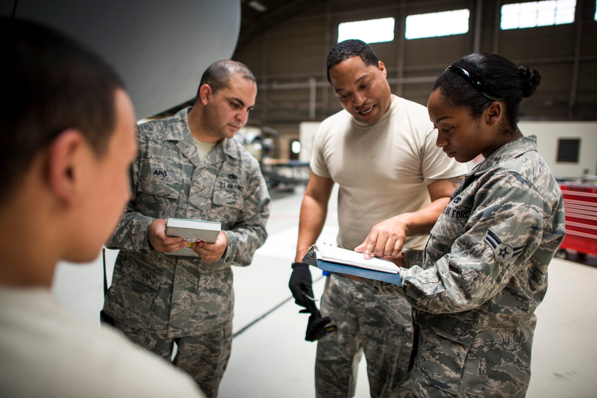 YOKOTA AIR BASE, Japan -- Tech. Sgt. Tavious Huff, center right, 374th Maintenance Squadron maintenance flight specialist section chief, reviews a technical order with Airman 1st Class Laketa Kinghorne, right, 374 MXS communications and navigation systems apprentice, at Yokota Air Base, Japan, July 25, 2012. Maintenance crews use technical orders to make sure they perform repairs and inspections correctly. (U.S. Air Force photo/Tech. Sgt. Samuel Morse)