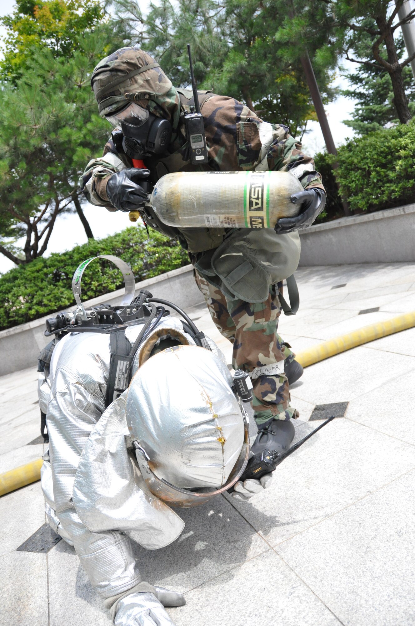A first responder replaces the air tank of a 51st Civil Engineer Squadron firefighter during operational readiness exercise Beverly Midnight 12-03 at Osan Air Base, Republic of Korea, July 25, 2012. During OREs Airmen highlight their ability to position, employ, and sustain forces and showcase operational readiness.BM 12-03 is the first ORE following the consolidated unit inspection in April.  (U.S. Air Force photo/Senior Airman Michael Battles)