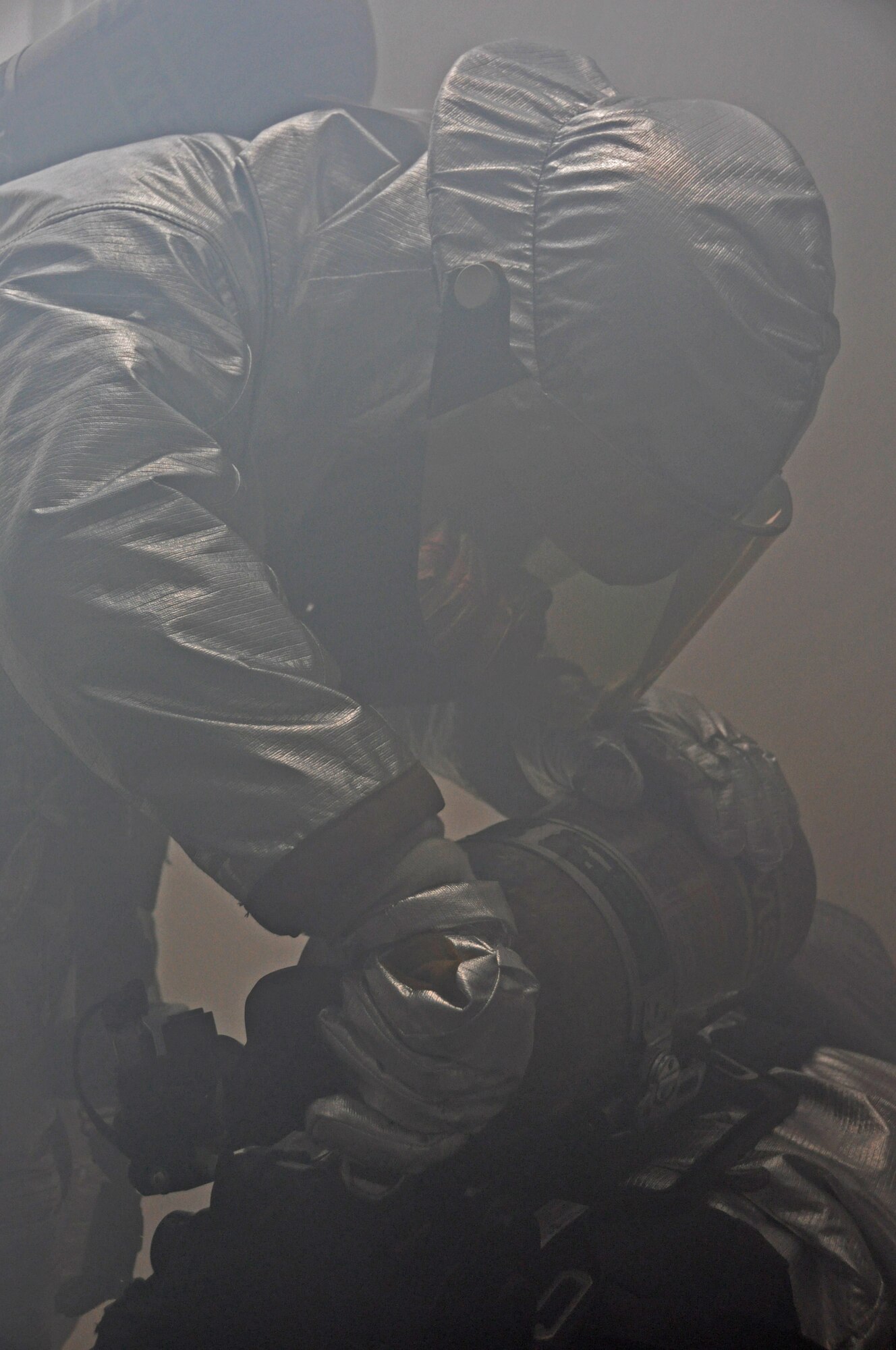 A firefighter from the 51st Civil Engineer Squadron fixes a fellow firefighters air tank after an attack during operational readiness exercise Beverly Midnight 12-03 at Osan Air Base, Republic of Korea, July 25, 2012. Exercise evaluation team members filled the building with smoke to simulate an actual fire. BM 12-03 is the fourth ORE for Osan in 2012. (U.S. Air Force photo/Senior Airman Michael Battles)
