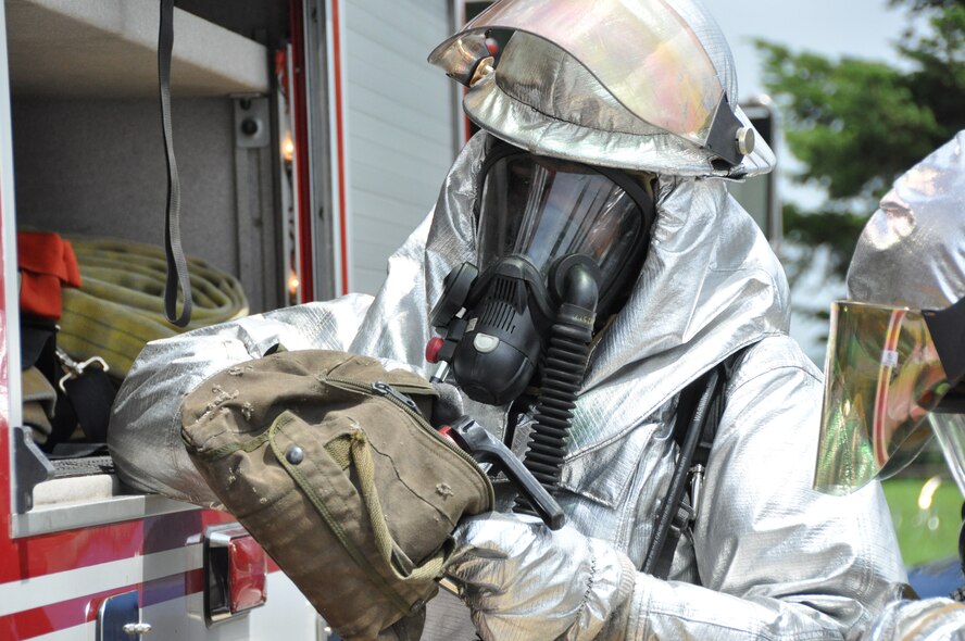 A firefighter from the 51st Civil Engineer Squadron distributes gear after an attack during operational readiness exercise Beverly Midnight 12-03 at Osan Air Base, Republic of Korea, July 25, 2012. Exercise evaluation team members filled the attacked building with smoke to simulate an actual fire. BM 12-03 is the fourth ORE for Osan in 2012. (U.S. Air Force photo/Senior Airman Michael Battles)
