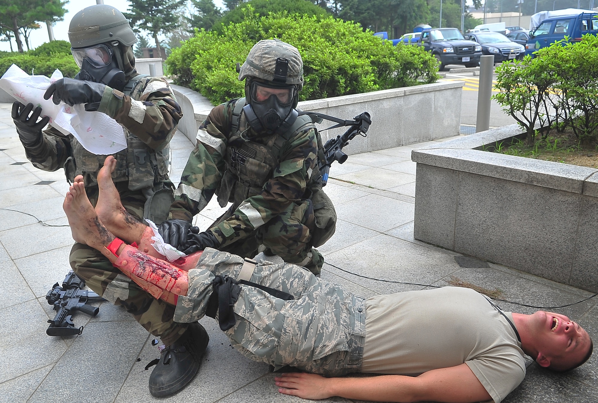 A pair of security sentries use expedient measures to protect the simulated wounds of a role player following a mass casualty event July 25, 2012, during exercise Beverly Midnight 12-03 at Osan Air Base, Republic of Korea.  Role players are pulled from 51st Fighter Wing units for the duration of the exercise.  Some of them are so new to the base, they have yet to join their units.  (Air Force photo/Tech. Sgt. Raymond Mills)