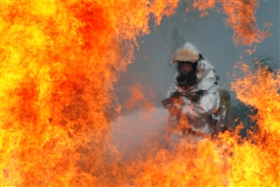 A U.S. Air Force firefighter sprays water at the fire of a simulated C-130 Hercules plane crash during operational readiness exercise Beverly Midnight 12-03 at Osan Air Base, Republic of Korea, on July 23, 2012.  The exercise tests the ability of personnel to defend the base and conduct daily operations during a heightened state of readiness.  