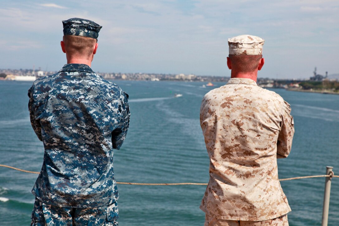 A sailor and Marine stand on the flight deck of the USS Peleliu as it leaves San Diego, July 18, beginning Composite Unit Training Exercise (COMPTUEX) 2012. The pre-deployment exercise will evaluate the ARGâ€™s ability to conduct integrated military operations and support the 15th Marine Expeditionary Unit as it conducts training operations at sea and ashore in a realistic training environment.