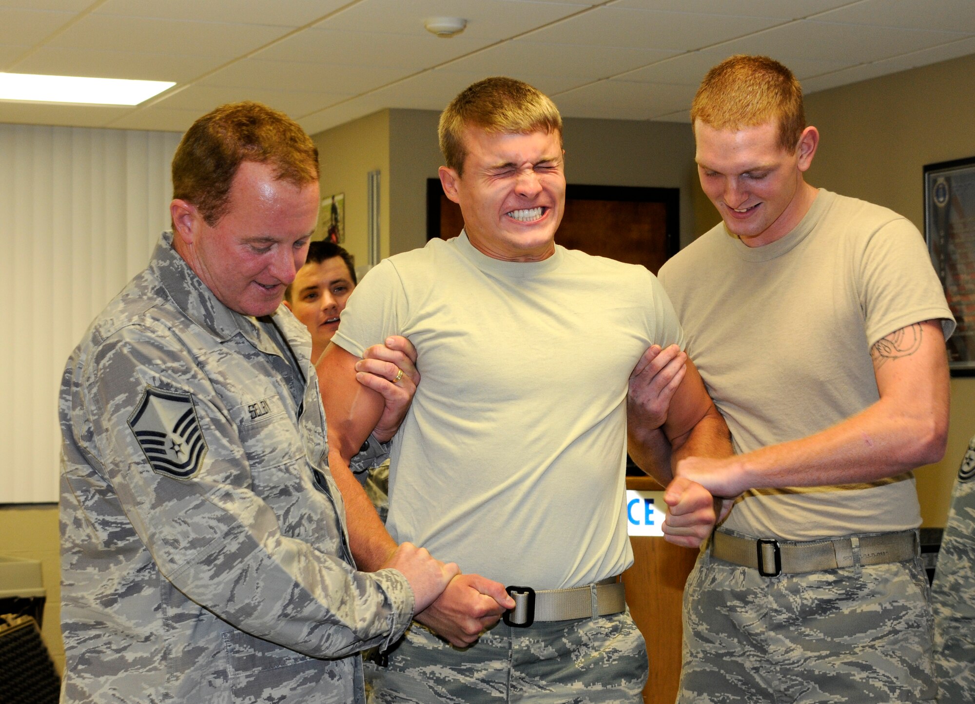 Master Sgt. John Selby, left, and Airman 1st Class Steven Frank, right, hold up Senior Airman Stephen Edwards as Master Sgt. Jason Reichert, back, operates a Taser stun gun during training at the 188th Security Forces Squadron July 15. (National Guard photo by Airman 1st Class Hannah Landeros/188th Fighter Wing Public Affairs)
