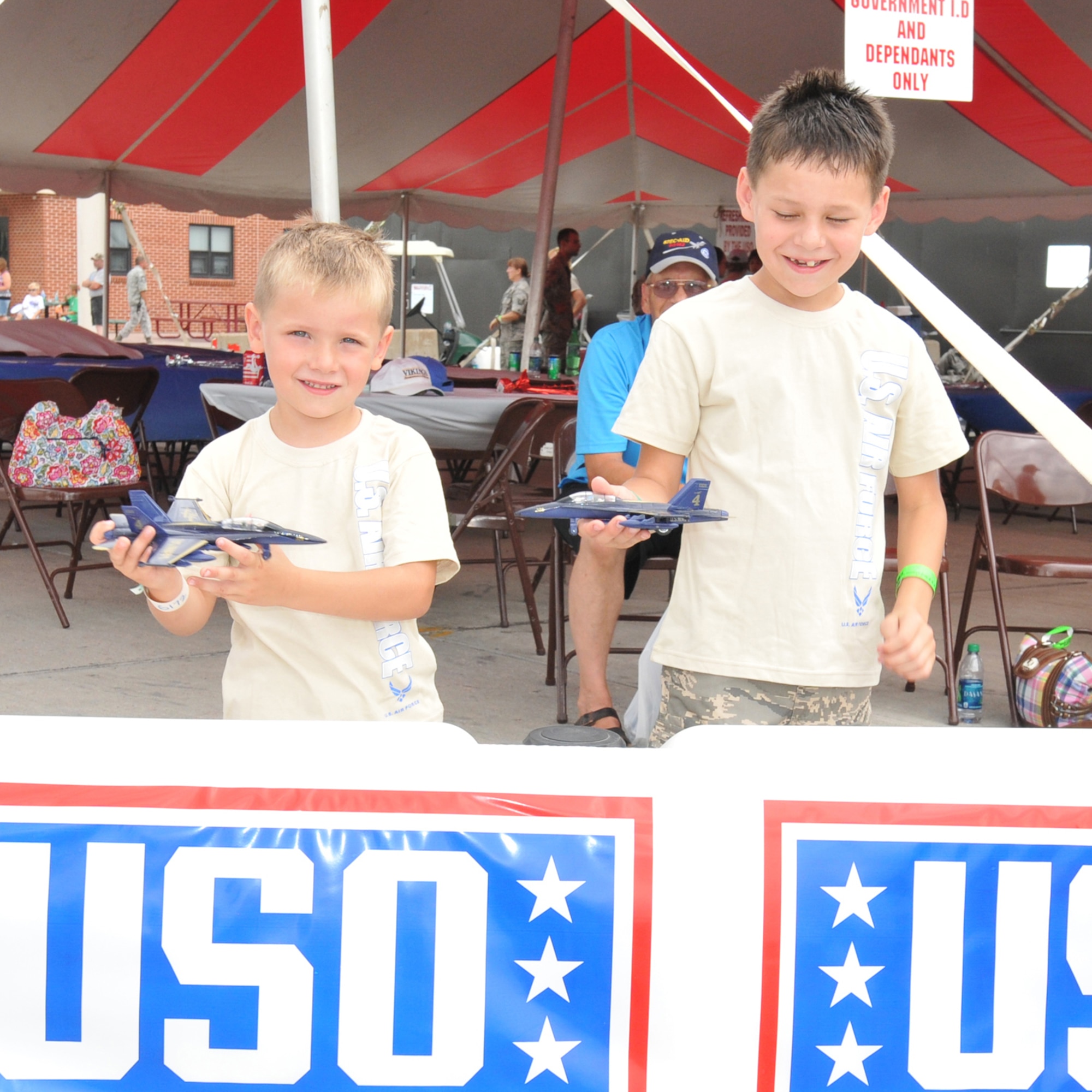 SIOUX FALLS, S.D. - Prestyn (left) and Peirce Stahl, sons of Staff Sgt. Matthew Stahl, 114th Logistics Readiness Squadron, enjoyed playing with toy airplanes under the watchful eye of their grandfather Jean Stahl. The three were resting in the United Services Organization tent during the Sioux Falls Airshow 2012 here July 21.(National Guard photo by Master Sgt. Christopher Stewart)(Released)