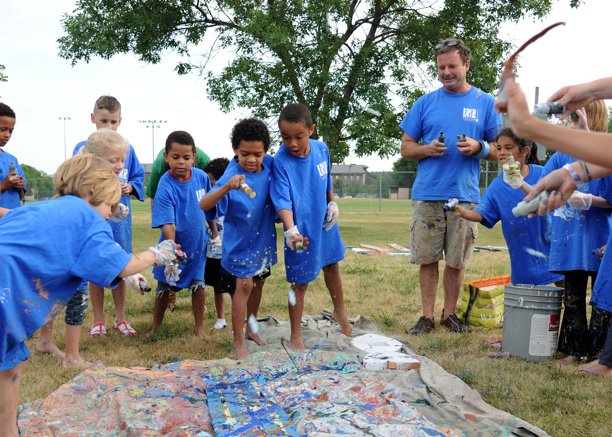 Exceptional Family Member Program Art Camp participants splash paint on a wooden plank, July 24, 2012, on Grand Forks Air Force Base, N.D.  About two dozen children participated in the camp and the completed project will be permanently mounted by the base pond.  (U.S. Air Force photo/Airman 1st Class Ashley N. Taylor)