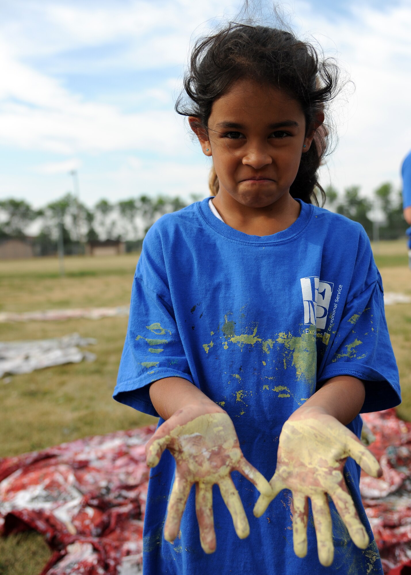 Gianna Gonzalez shows off her paint-covered hands at the Exceptional Family Member Program Art Camp, July 24, 2012, on Grand Forks Air Force Base, N.D.  About two dozen children participated in the camp and the completed project will be permanently mounted by the base pond. (U.S. Air Force photo/Airman 1st Class Ashley N. Taylor)