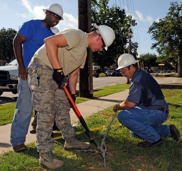 Shawn Jackson and Robert Gardner, 2nd Civil Engineer Squadron electric shop, assist Staff Sgt. Christopher Wells, 2 CES electric shop, as he cuts a guy wire on Barksdale Air Force Base, La., July 26.  Left over wire from a previous power pole was removed because it obstructed the crew?s ability to repair a damaged pole. (U.S. Air Force photo/Airman 1st Class Andrew Moua)(RELEASED)