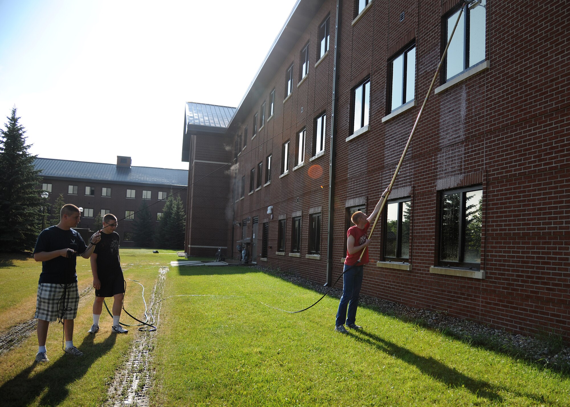 Airmen 1st Class Jacob Davidson and Gregory Akin, 69th Maintenance Squadron, assist fellow squadron member Airman Xevious Alde, while washing windows at Barnes Hall on July 25, 2012, on Grand Forks Air Force Base, N. D.  All dormitories were washed this week by volunteers as part of a new effort to encourage pride in ownership of base facilities.  (U.S. Air Force photo/Airman 1st Class Ashley N. Taylor)  