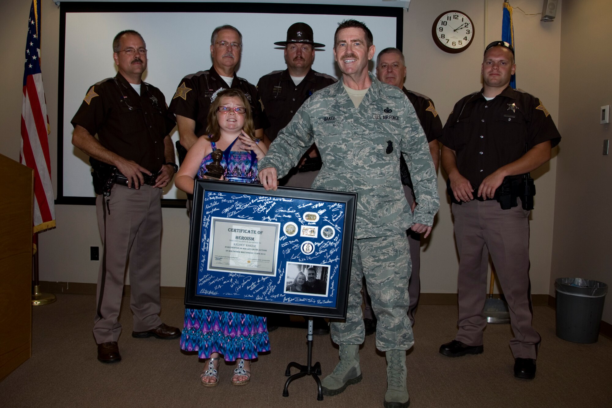 GRISSOM AIR RESERVE BASE, Ind. -- Kelsey Baker poses with her father Master Sgt. Mitchell Baker, 434th Security Forces Squadron squad leader, after she received awards during a ceremony at Grissom July 8. She was recognized for helping to save her father's life after he suffered a stroke. The 434th SFS, Grissom Rising 6 and the Fulton County Sheriff's Department presented her the awards. (U.S. Air Force photo/Staff Sgt. Carl Berry)