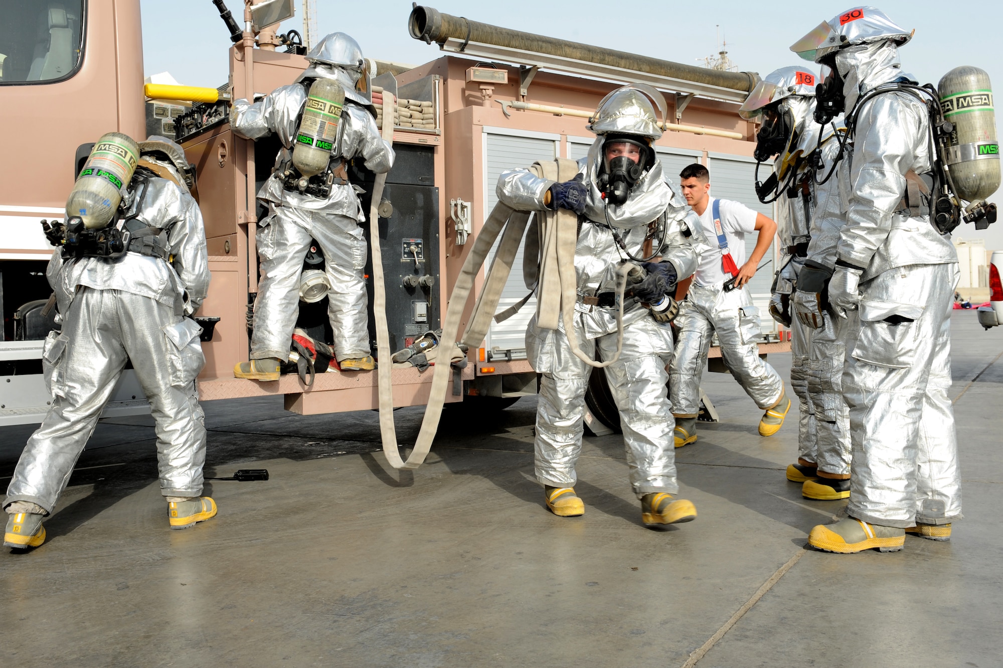 SOUTHWEST ASIA - Members of the 380th Expeditionary Civil Engineer Squadron Fire Department pull a hose from their fire truck to fight a simulated building fire during a major accident response exercise at the 380th Air Expeditionary Wing July 25, 2012. The exercise tested the wing's ability to respond to a major accident. (U.S. Air Force photo/Master Sgt. Scott MacKay)