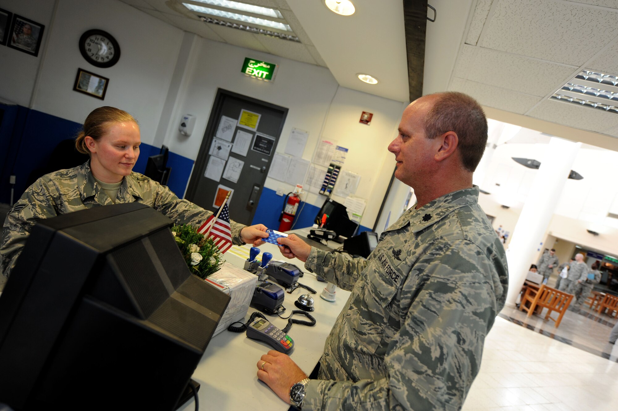 U.S. Air Force Senior Airman Chelsea Kemper, 379th Expeditionary Communications Squadron postal clerk, assists Lt. Col. Donald Grannan, 379th ECS commander with using the new debit/credit card machine at the 379th Air Expeditionary Wing Post Office in Southwest Asia, July 24, 2012. The 379th ECS is the first Air Force contingency in the AOR to utilize the debit/credit card transaction machine. Kemper is deployed from Ramstein Air Base, Germany and is a native of Gettysburg, Pa. (U.S. Air Force photo/Staff Sgt. Sheila deVera)