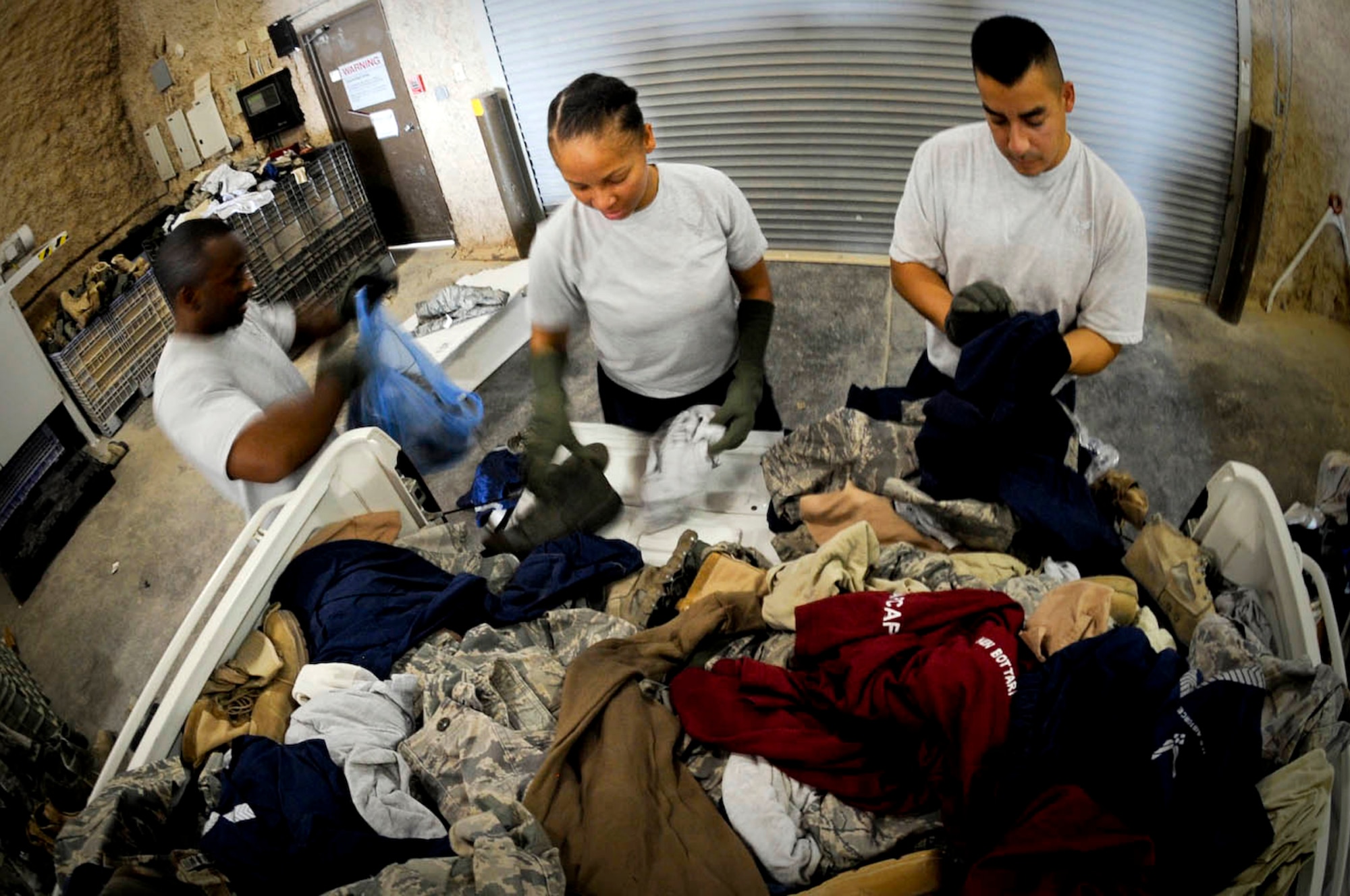 U.S. Air Force Master Sgt. Richard Page (left to right), Tech. Sgt. Tamecca Neely and TSgt. Michael Benitez, all assigned to the 379th Air Expeditionary Wing, sort through discarded uniform prior to shredding unserviceable uniforms in Southwest Asia, July 24, 2012. (U.S. Air Force photo/Staff Sgt. Sheila deVera)