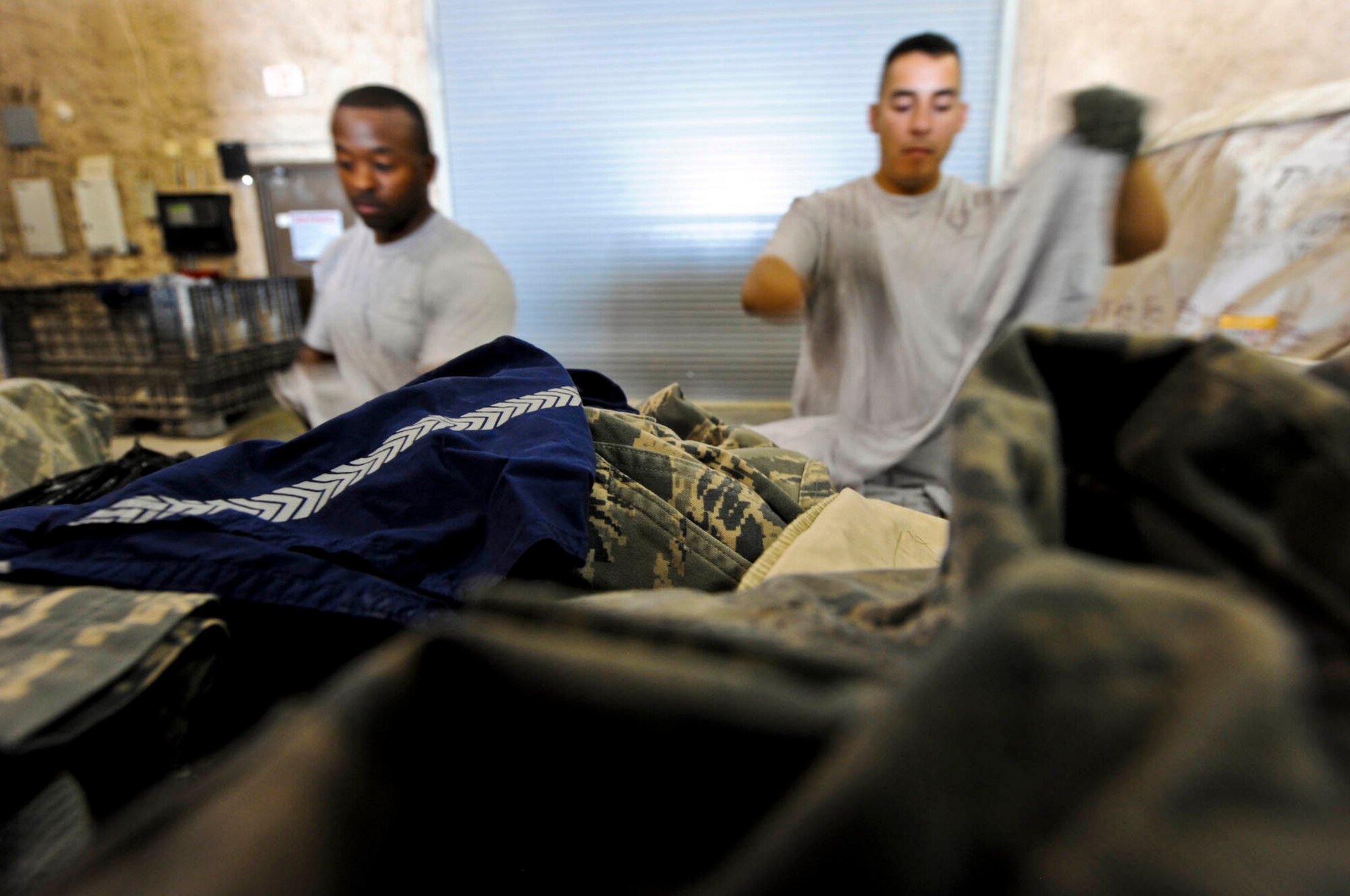 U.S. Air Force Master Sgt. Richard Page (left), Ground Safety manager, and Tech. Sgt. Michael Benitez, Joint Security Coordination Center non-commissioned officer in charge, sort through discarded uniform items prior to shredding unserviceable uniforms in Southwest Asia, July 24, 2012. Page and Benitez are both assigned to the 379th Air Expeditionary Wing. (U.S. Air Force photo/Staff Sgt. Sheila deVera)