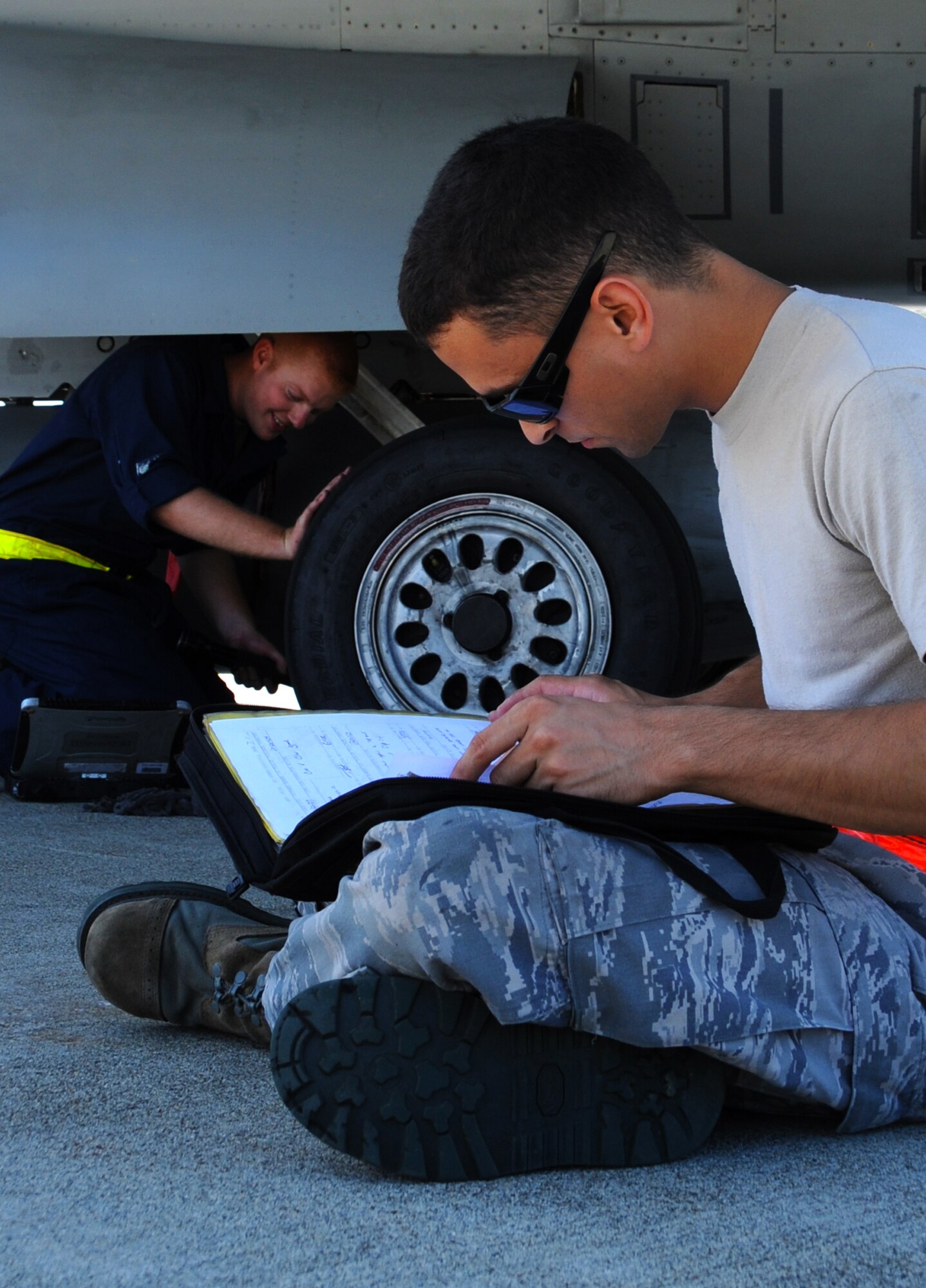 U.S. Air Force Staff Sgt. Robert Shawl, front, 35th Maintenance Squadron sheet metal technician, signs brake-line repair forms as Senior Airman Zachary Hurt, 14th Fighter Squadron aircraft maintainer, inspects landing gear at Misawa Air Base, Japan, July 26, 2012.  Inspections are done daily on the Fighting Falcons to keep pilots safe and ensure the aircraft are ready to fly at a moment’s notice.  (U.S. Air Force photo by Staff Sgt. April Quintanilla)