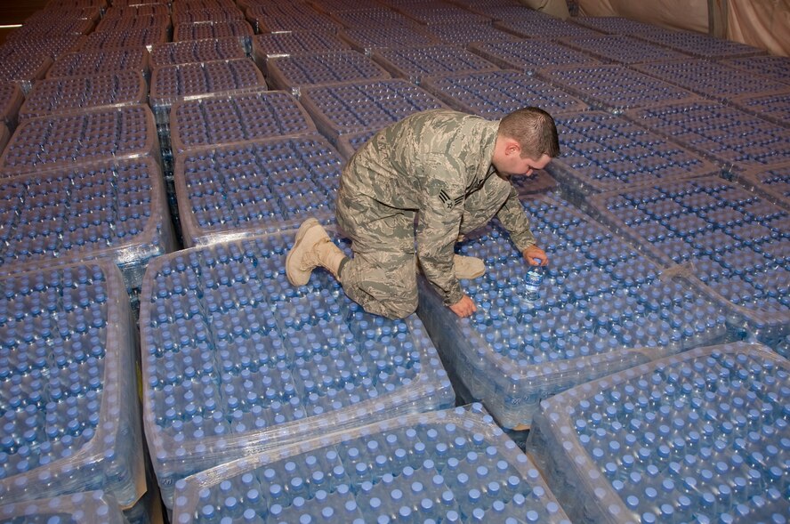 Senior Airman Ryan Smith, 379th Expeditionary Medical Group Bioenvironmental environmental program manager, pulls a random bottle of water from a pallet of water with a specific production date. Smith pulls and tests random bottles from every shipment of water to ensure all water is free of any form of bacteria. More than 1.3 million bottles of water are consumed at this installation every month. (U.S. Air Force photo/Senior Airman Bryan Swink)