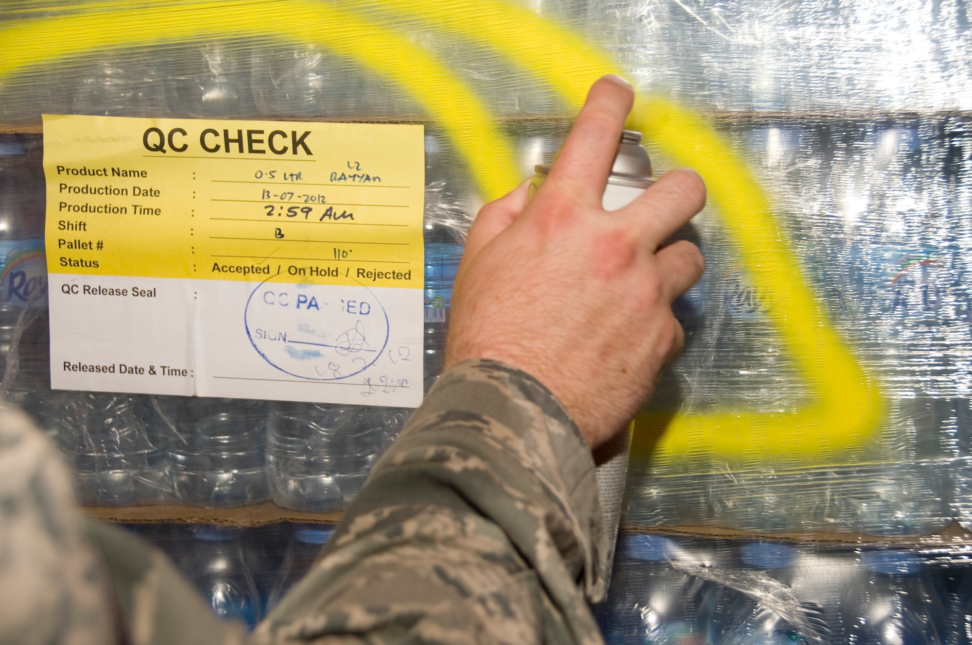 Senior Airman Ryan Smith, 379th Expeditionary Medical Group Bioenvironmental environmental program manager, spray paints a pallet of bottled water July 20, 2012. After each lot of water has been cleared and deemed safe for consumption, Smith marks the pallet of water with a large, yellow ‘C’. He conducts bacteriological tests on every batch of water received. (U.S. Air Force photo/Senior Airman Bryan Swink)