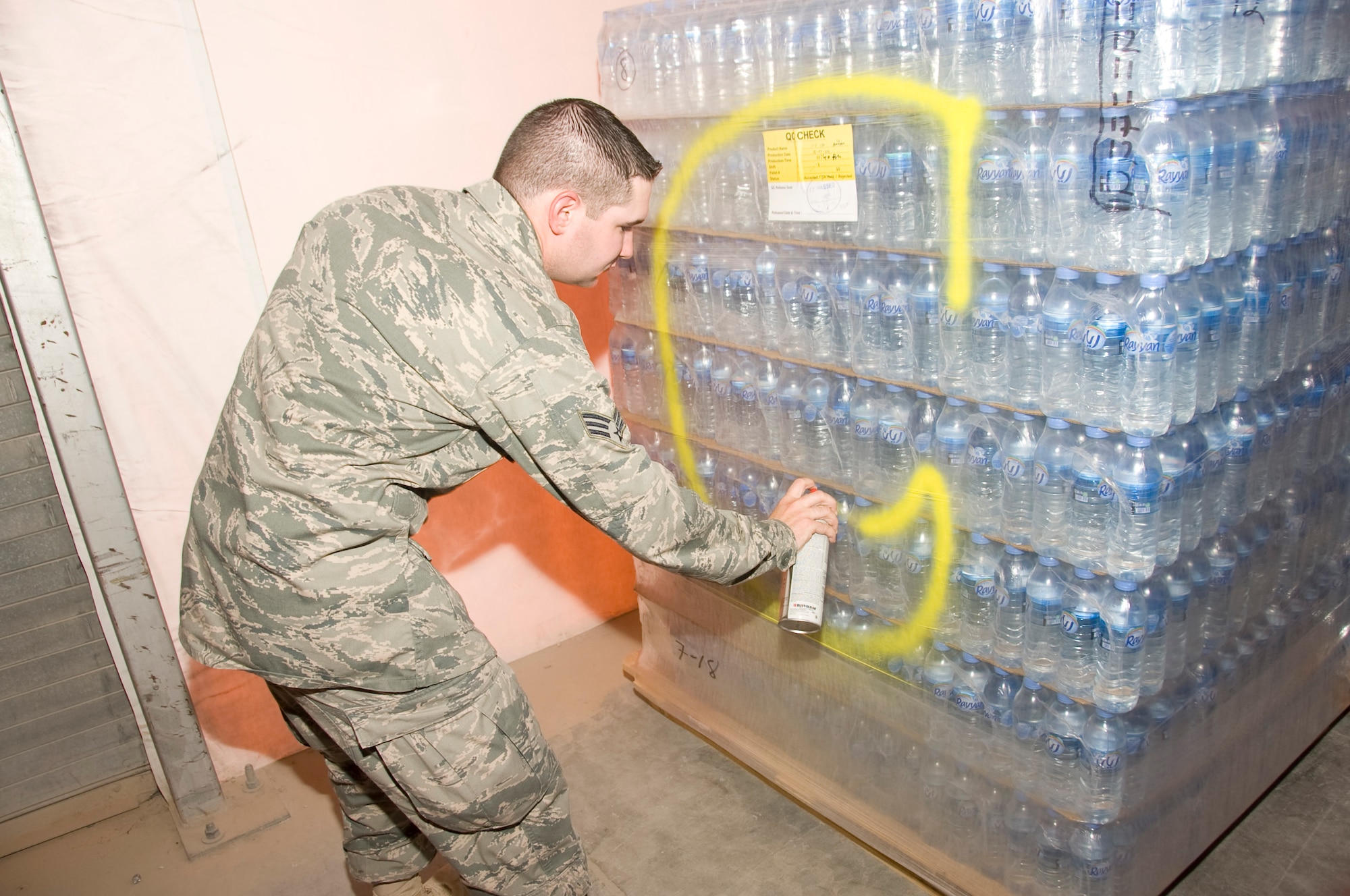 Senior Airman Ryan Smith, 379th Expeditionary Medical Group Bioenvironmental environmental program manager, spray paints a pallet of bottled water July 20, 2012. After each lot of water has been cleared and deemed safe for consumption, Smith marks the pallet of water with a large, yellow ‘C’. He conducts bacteriological tests on every batch of water received. (U.S. Air Force photo/Senior Airman Bryan Swink)