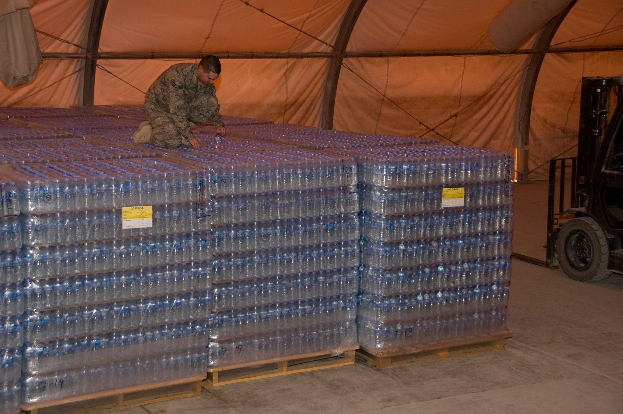 Senior Airman Ryan Smith, 379th Expeditionary Medical Group Bioenvironmental environmental program manager, pulls a random bottle of water from a pallet of water with a specific production date. Smith pulls and tests random bottles from every shipment of water to ensure all water is free of any form of bacteria. More than 1.3 million bottles of water are consumed at this installation every month. (U.S. Air Force photo/Senior Airman Bryan Swink)
