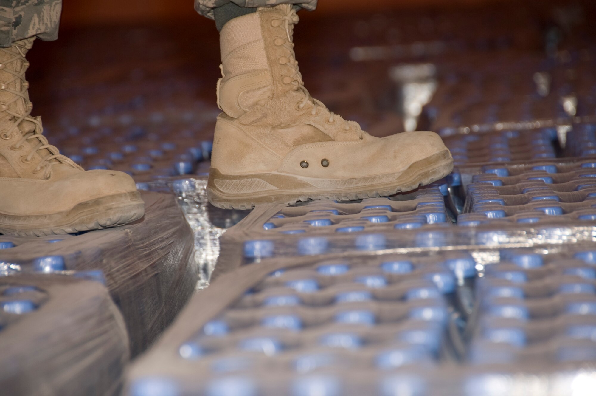 Senior Airman Ryan Smith, 379th Expeditionary Medical Group Bioenvironmental environmental program manager, walks across thousands of bottles of water July 20, 2012 to reach a pallet of water which has a specific production date. Smith pulls and tests random bottles from every shipment of water to ensure all water is free of any form of bacteria. More than 1.3 million bottles of water are consumed at this installation every month. (U.S. Air Force photo/Senior Airman Bryan Swink)