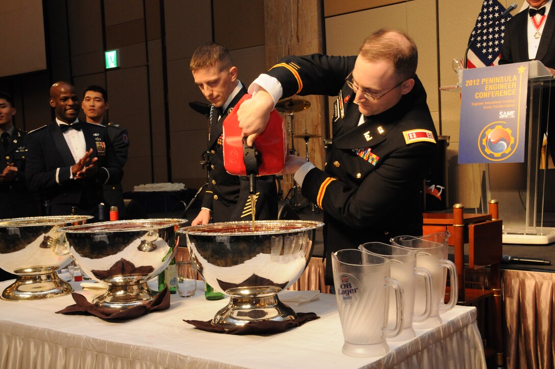 Capt. Matthew Larocco, commander of Company C, 1st Brigade Special Troops Battalion, pours Red Bull into the grog bowl at the Peninsula Engineer Conference Dining Out April 5. 
