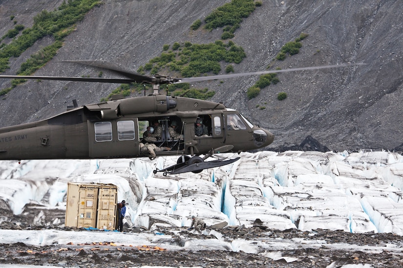 A helicopter hovers above icy terrain.
