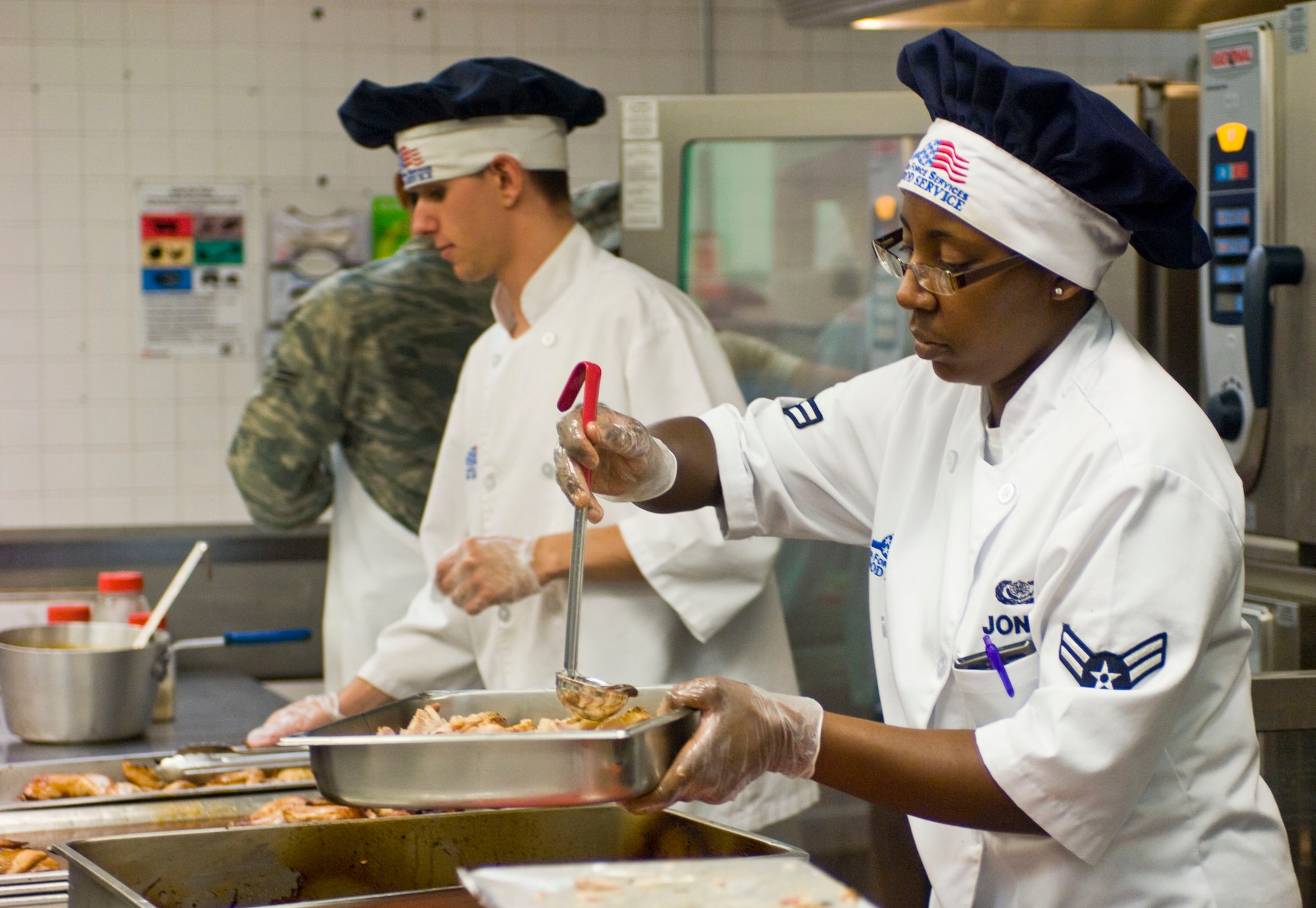 Airman 1st Class Jacqueline Jones and Airman 1st Class Joseph Hammersten, 99th Force Support Squadron food services specialists, prepare food July 23, 2012, at the Crosswinds Dining Facility on Nellis Air Force Base, Nev. The dining facility offers Airmen healthy food alternatives in accordance with Air Force standards. (U.S. Air Force photo by Senior Airman Jack Sanders)
