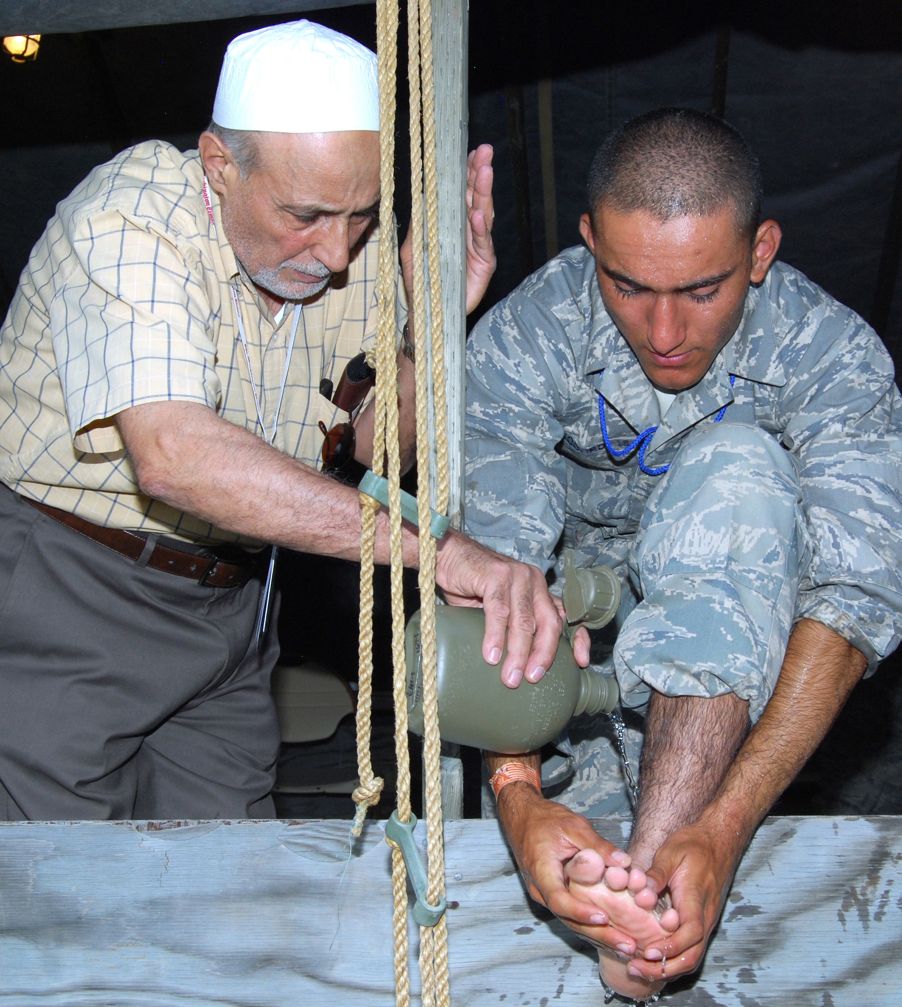 Imam Mohamed Jodeh helps Basic Cadet Wasim Soomro perform wudu prior to evening prayers in the Muslim chapel at Jacks Valley July 22, 2012. Wudu is a form of ablution, or ritual purification, that consists of washing one's hands, feet, mouth and face before praying or touching the Qur'an. Jodeh leads Muslim services as part of the Air Force Academy's lay leader program. (U.S. Air Force photo/Don Branum)