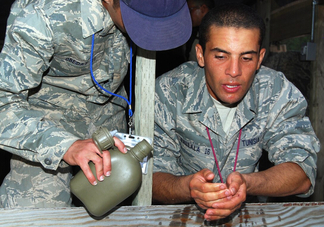 Basic Cadet Omar Obeidat helps Basic Cadet Mohammed Gallala perform wudu in preparation for evening prayer in Jacks Valley July 22, 2012. Wudu is a Muslim form of ritual purification that consists of washing one's hands, feet, mouth and face before praying or touching the Qur'an. Obeidat is a native of Jordan, and Gallala is a native of Tunisia. (U.S. Air Force photo/Don Branum)