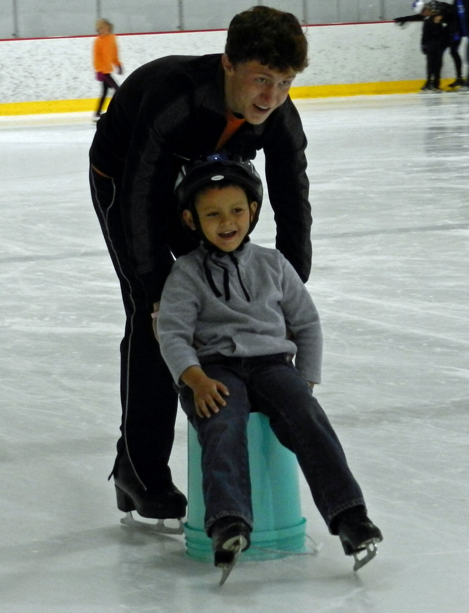 A volunteer pushes Jayden Bleisch, exceptional family member, across the ice rink on a bucket at C3 Skating Therapy camp. The Exceptional Family Member Program sponsored the camp for 18 children in the EFMP program. The camp was held at Honnen Ice Arena in downtown Colorado Springs, Colo. July 16-20. (courtesy photo)