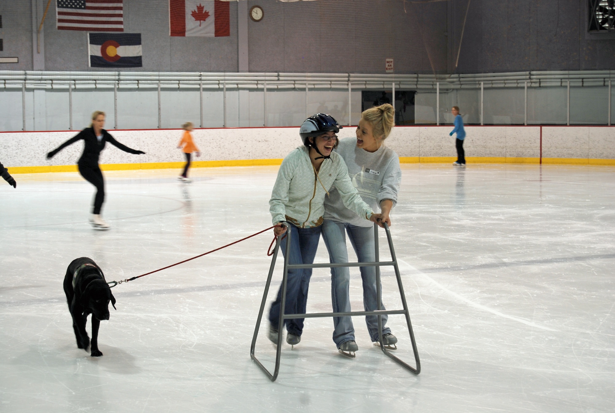 A volunteer helps Kimiko Bullis, exceptional family member, (left) learn to skate with the assistance of a walker and her seeing eye dog, Drifter, July 20. The Exceptional Family Member Program sponsored C3 Skating Therapy camp for 18 children in the EFMP program. The camp was held at Honnen Ice Arena in downtown Colorado Springs, Colo. July 16-20. (U.S. Air Force photo/Lea Johnson)