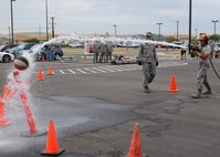 2nd Lt. Christopher Foti, 341st Security Forces Squadron flight commander, uses a fire hose to knock a basketball off of a cone as Tech. Sgt. Jeremy Wray, 341st Civil Engineer Squadron firefighter, waits to take the hose before he moves to the Bucket Brigade.  Wray along with other members of Malmstrom’s fire department were at the Fire Muster competition cheering on other members participating.  (U.S. Air Force photo/Airman 1st Class Cortney Paxton)