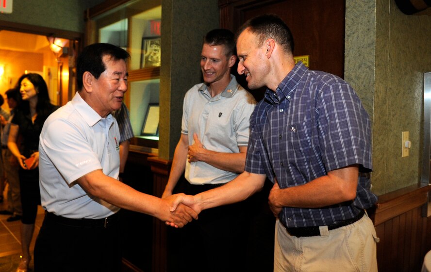 Chairman Cho Nam-sok, left, 2007 United States Forces Korea Good Neighbor Program Award Winner, shakes hands with Lt. Col. Anthony D. Abernathy, right, 8th Operations Group vice commander, after greeting Col. Douglas Nikolai, 8th Fighter Wing vice commander, at a Korean-American Gunsan Association dinner July 26, 2012, at Kunsan Air Base, Republic of Korea. The KAGA is a way for base leadership and local businessmen to maintain a positive relationship. (U.S. Air Force photo/Senior Airman Brigitte N. Brantley)