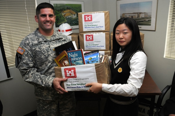 Maj. John Burrescia, U.S. Army Corps of Engineers, Far East District Central Resident Office, presents books to a student from Pyongtaek Girls' High School Oct. 11 as part of FED's Good Neighbor Program. The books were collected during FED's Good Neighbor Program book drive which also received generous support from the National Honor Society at Seoul American High School. The schools will use the books to build an English library. (Photo by Patrick Bray)