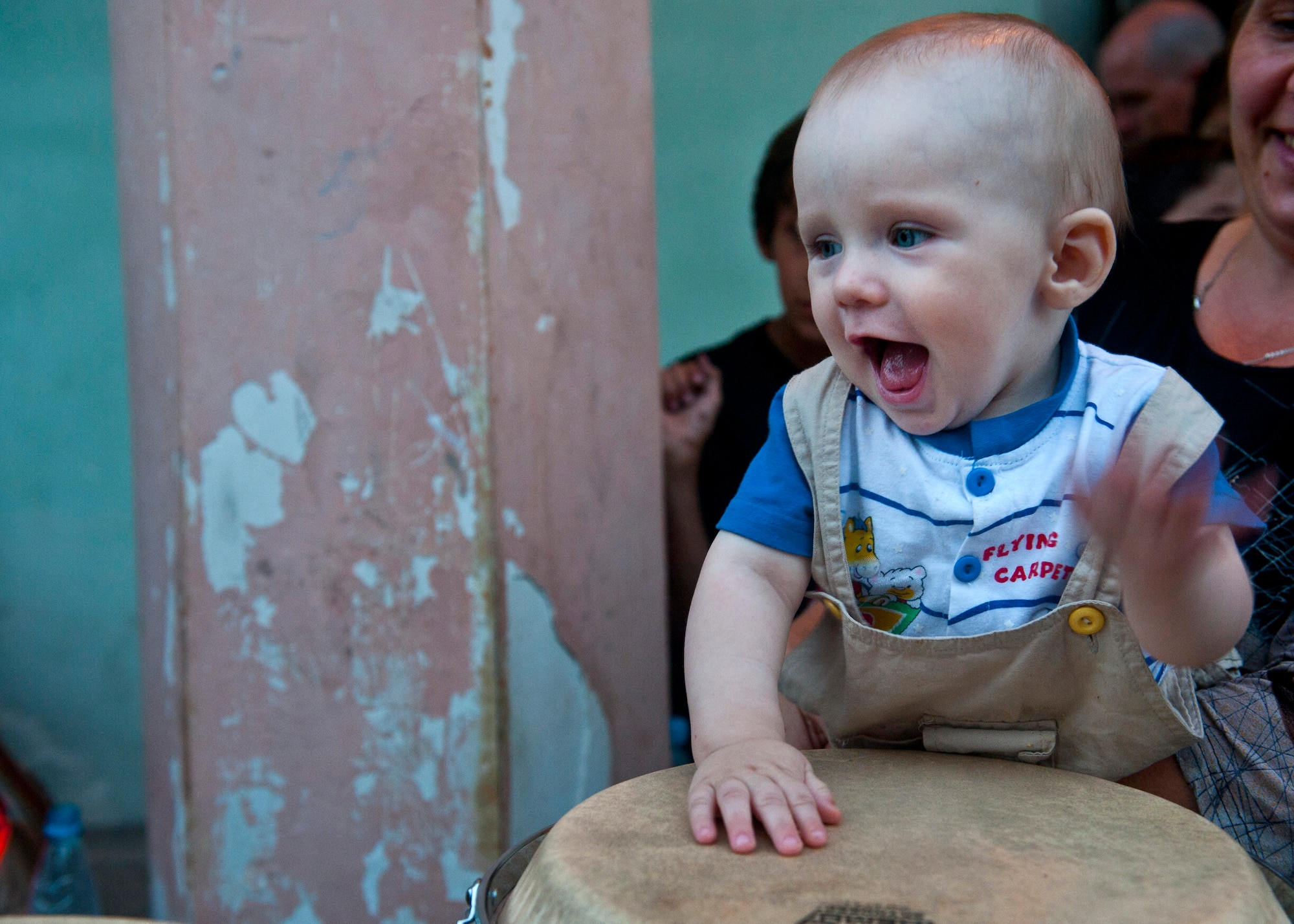 Ishevka, 10 months, beats on Conga drums after a U.S. Air Forces Central Band "Vector" performance at the Maevka House of Culture in Maevka Village, Kyrgyzstan, July 27, 2012. After the performance, Vector band members interacted with the audience and let them play with different instruments. (U.S. Air Force photo/Senior Airman Brett Clashman)