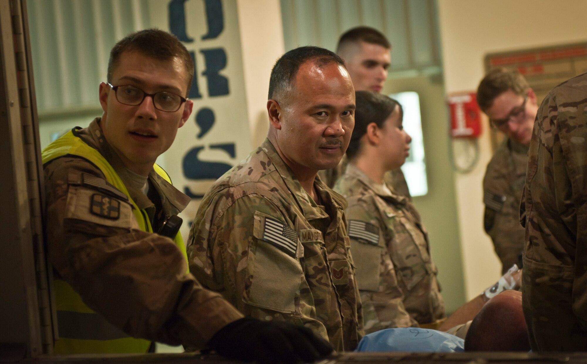 A1C Robert DeSantis (left), 455th Expeditionary Medical Operation Squadron medical technician at the Craig Joint Theater Hospital, and TSgt Artemio Mangrobang (right), a Contingency Aeromedical Staging Facility volunteer from the 455th Expeditionary Logistics Readiness Squadron, prepare to move a patient onto a hospital bus at Bagram Airfield, Afghanistan, July 23, 2012. The CASF is the relay between the CJTH and aeromedical evacuation missions. (U.S. Air Force Photo/Capt. Raymond Geoffroy)