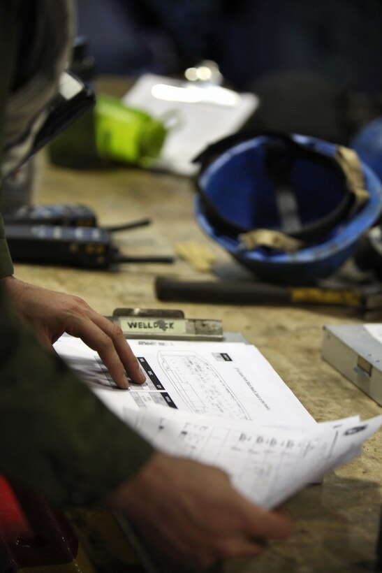 Staff Sgt. Brandon L. Sims, well deck combat cargo assistant, Combat Cargo, Ship’s Company, USS Peleliu, reviews the load plan for the well deck of the USS Peleliu before unloading vehicles from a landing craft utility, July 28. Sims, 30, is a native of Livingston, Texas.