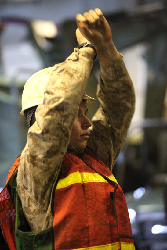 Lance Cpl. Jon Atkinson, a Marine with Combat Cargo, Ship’s Company, USS Peleliu, guides a vehicle inside the well deck of the USS Peleliu during Composite Training Unit Exercise, July 28.  The pre-deployment training event evaluates the Peleliu Amphibious Ready Group’s ability to conduct integrated military operations at sea and ashore in a realistic training environment.